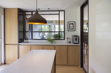 Une cuisine ferm&eacute;e mais ouverte sur le salon gr&acirc;ce &agrave; une grande cloison vitr&eacute;e